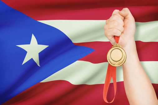 Sportsman holding gold medal with flag on background - Commonwealth of Puerto Rico