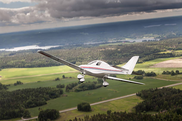 Ultralight An ultralight flying above a flat landscape with forests, fields and river. The sky is cloudy, like before a thunderstorm ultralight stock pictures, royalty-free photos & images