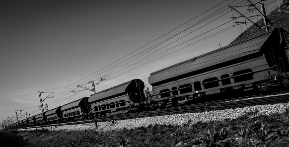 A long freight train hauls cargo across the country for consumer and industry consumption. Black and white.
