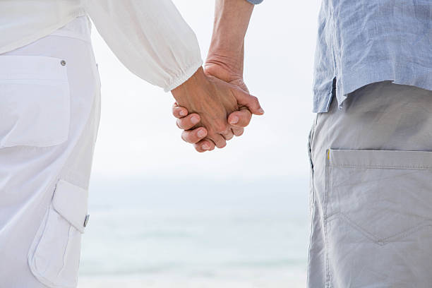 istock Happy couple holding hands and looking at the sea 484068610