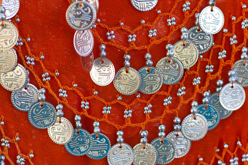 An ornate orange bellydancing scarf with jingly silver coins (close-up).