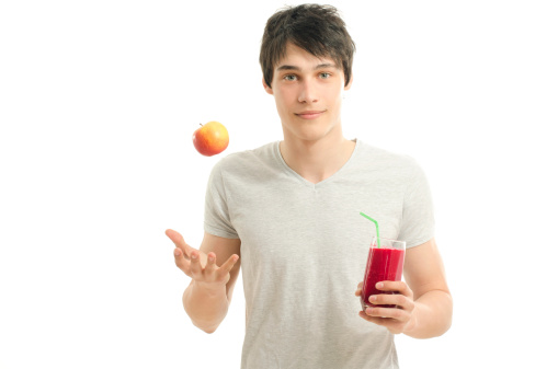 Man preparing a red smoothie from bio apples, eating healthy for an active life,dieting. Man throwing an apple in the air