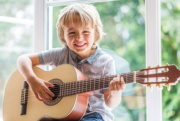 petit garçon jouant guitare acoustique - guitar child music learning photos et images de collection
