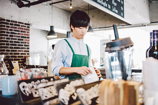 Young Japanese man working in cafe. Japanese waiter working behind bar counter. men close up 20s asian ethnicity stock pictures, royalty-free photos & images