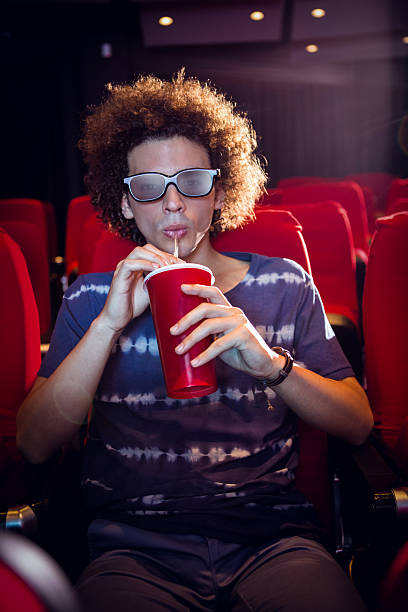 istock Young man watching a 3d film and drinking soda 484073412