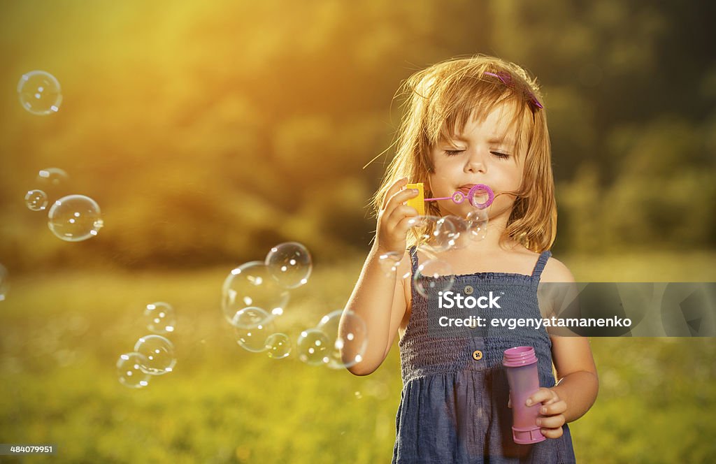 little girl Soplando burbujas de jabón en la naturaleza - Foto de stock de Soplador de burbujas de jabón libre de derechos