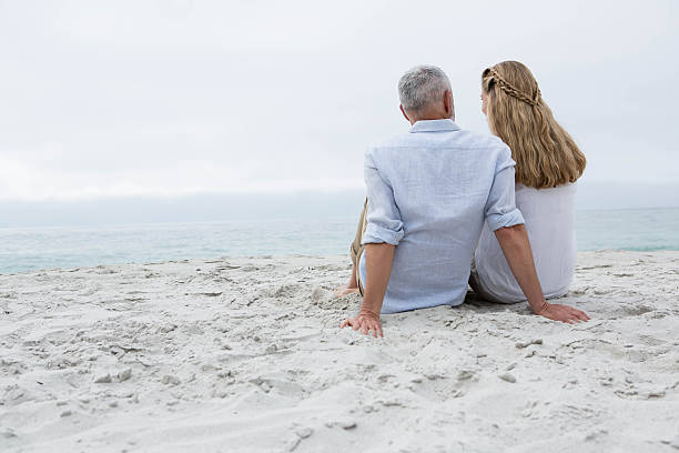 istock Happy couple sitting on the sand 484080684