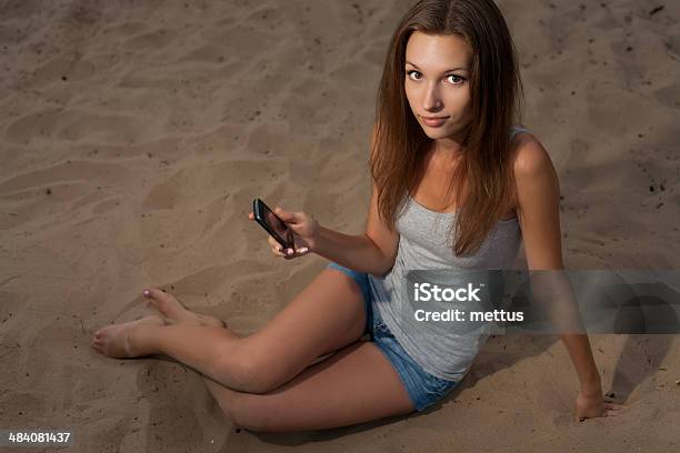 Mulheres Com Telemóvel Sentado Na Areia - Fotografias de stock e mais imagens de Adulto - Adulto, Ao Ar Livre, Areia