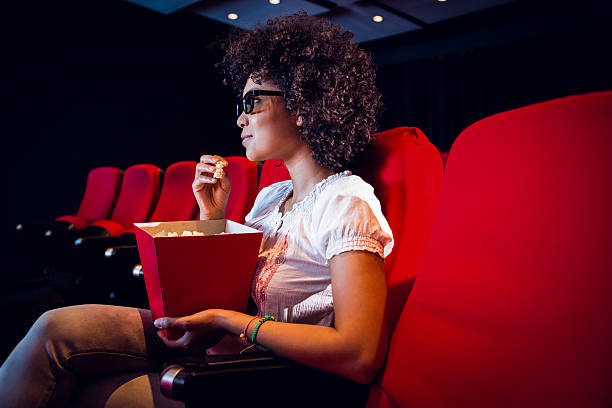 istock Young woman watching a 3d film and eating pop corn 484083494