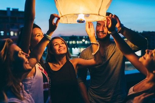 Happy friends on a rooftop party holding a sky lantern