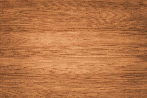 High quality brown wooden background. This background features a distinguished wood grain pattern complete with wavy lines. The colour of the wood appears darker near the left and right edges, but becomes lighter near the middle.