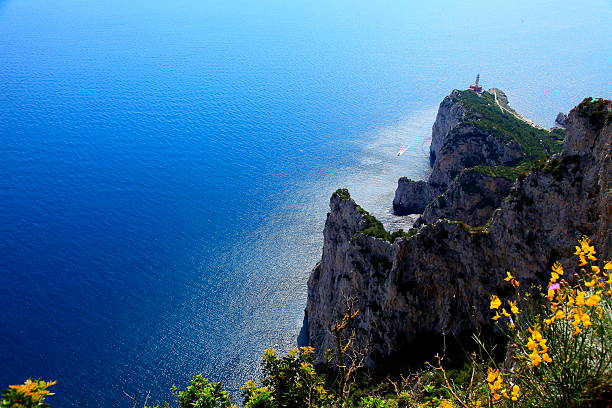 Mediterranean sea from above Capri Cliff, lighthouse and ship crossing water against Sun - Coast - Bay of Naples, Italy.