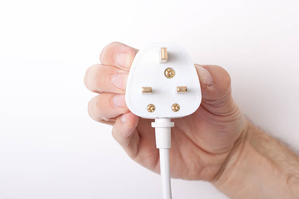 Hand holding electrical plug Male hand holding an electrical plug three pin plug stock pictures, royalty-free photos & images