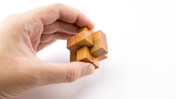 Hand holding piece of wooden block cube puzzle.
