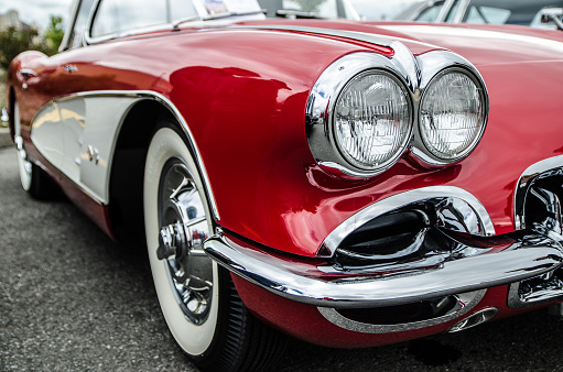 Quebec, Canada - September 09, 2012: Close up on the front of an antique red and white Corvette with its headlight, chrome and Whitewall tires during an car show exposition at daytime in a shopping mall outside parking lot