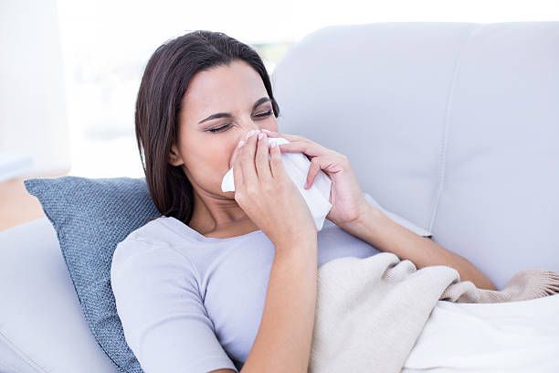 istock Sick brunette lying on the couch and blowing her nose 484115520