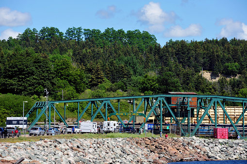 Canso Causeway, Canada – August 6, 2015: The swing bridge on the Canso Causeway allows a ship to pass through and blocking traffic from entering Cape Breton Island in Nova Scotia.  The causeway was built with rock from nearby Cape Porcupine.