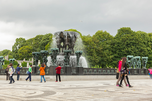 Oslo, Norway - August 11, 2015: Group of tourists visiting Gustav Vigeland Sculpture Park. In the background you can see the monolith that is the centerpiece of the park.