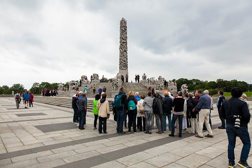 Oslo, Norway - August 11, 2015: Group of Asian tourists visiting Gustav Vigeland Sculpture Park. In the background you can see the monolith that is the centerpiece of the park.