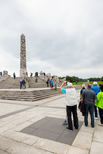 Oslo, Norway - August 11, 2015: Group of Asian tourists visiting Gustav Vigeland Sculpture Park. In the background you can see the monolith that is the centerpiece of the park.