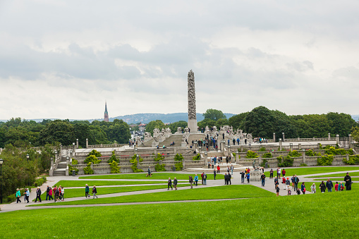 Oslo, Norway - August 11, 2015: Group of tourists visiting Gustav Vigeland Sculpture Park. In the background you can see the monolith that is the centerpiece of the park.