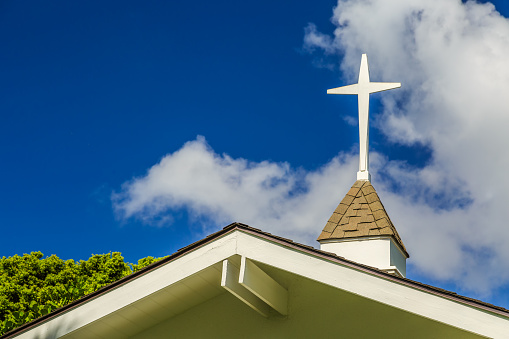 The steeple and cross on the roof of a small chapel