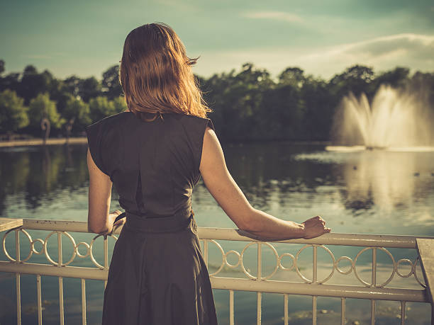istock Young woman standing by lake at sunset 484120056