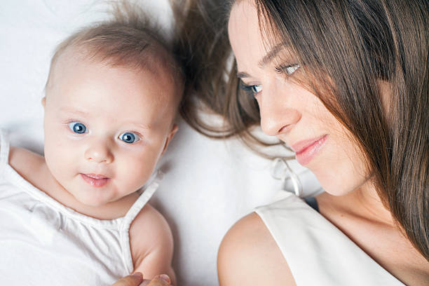 istock Happy mother with a baby lying on a white bed 484123122
