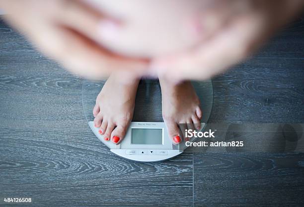 Pregnant Woman Weighing Herself On A Bathroom Scale Stock Photo - Download Image Now