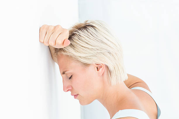istock Sad blonde woman with her head on wall 484131326