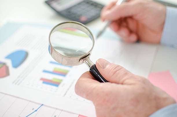 istock Businessman checking a graph with a magnifying glass 484132538
