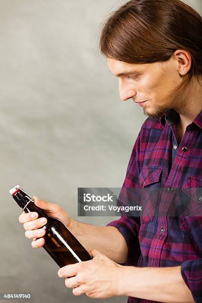 Young Man Holding A Beer Bottle On Grey Stock Photo - Download Image Now - 2015, Adult, Alcohol - Drink