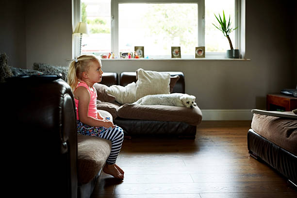 istock Cute little girl sitting alone on sofa 484151236