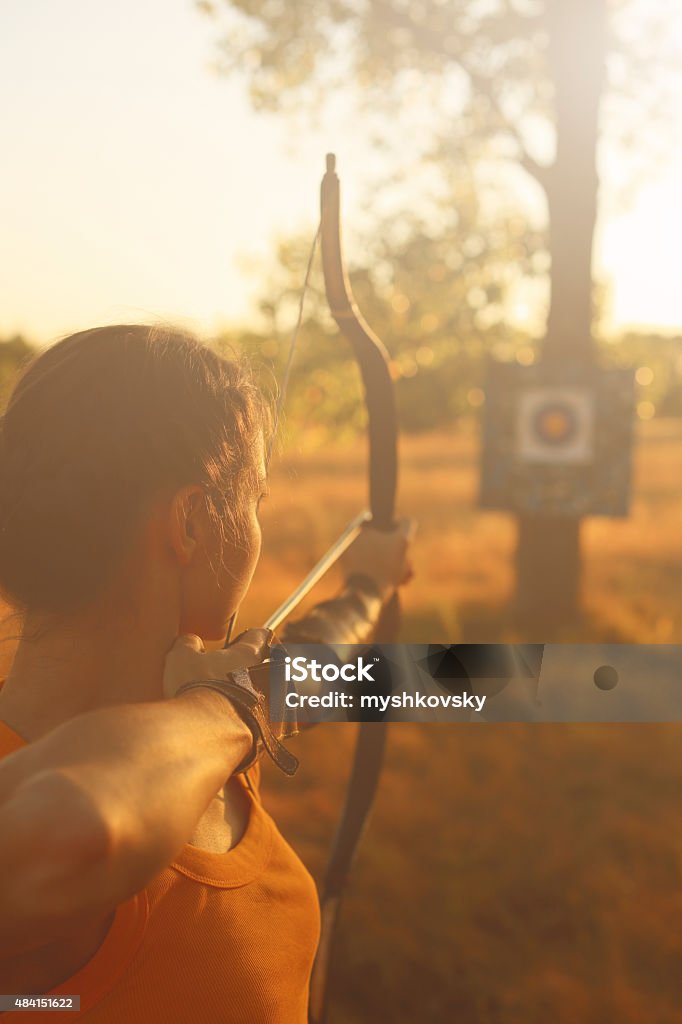 Mujer en el campo de archer al atardecer - Foto de stock de Tiro con arco libre de derechos