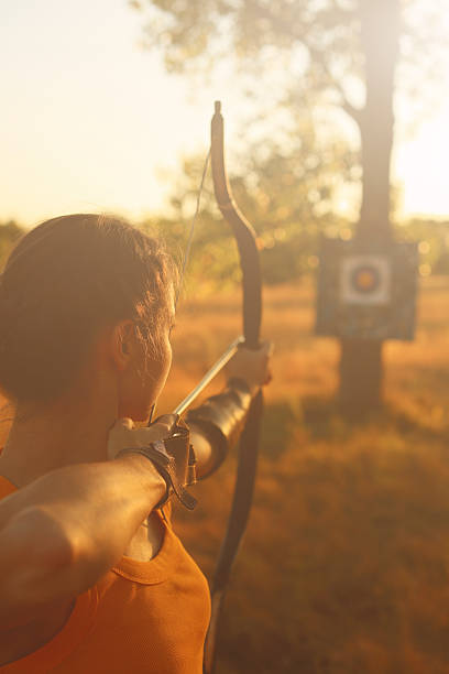 Female archer in the field at sunset