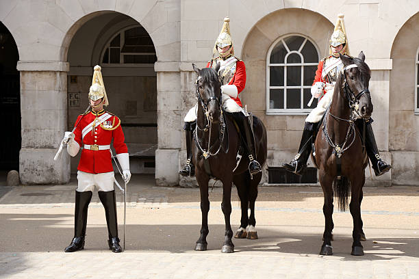 Queen's Life Guard London, England - June 27, 2015: Queen's Life Guard after The Guard Changing Ceremony in front of The Buckingham Palace, on The Mall. The Queen's Life Guard is provided by men of the Household Cavalry Mounted Regiment (HCMR) at Horse Guards. The HCMR consists of a Squadron of The Life Guards, who wear red tunics and white plumed helmets, and a Squadron of The Blues and Royals (Royal Horse Guards and 1st Dragoons) with blue tunics and red plumed helmets. The Guard Changing Ceremony takes place each weekday at 11 o'clock and at 10 o'clock on Sundays. morph transition stock pictures, royalty-free photos & images