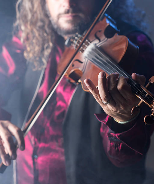 istock handsome man playing classical violin through blue smoke 484156886