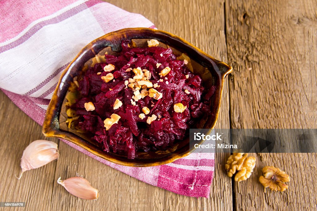 Grated beet Grated beet (beetroot) with walnuts over rustic wooden table 2015 Stock Photo