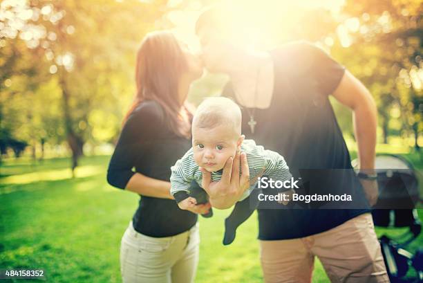 Father Holds Newborn Baby On Arm While Kissing The Mother Stock Photo - Download Image Now