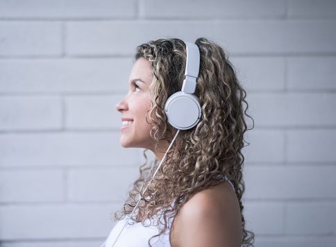 Portrait of a casual woman listening to music with headphones looking happy