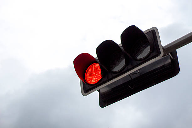istock red traffic light in the overcast sky 484161168