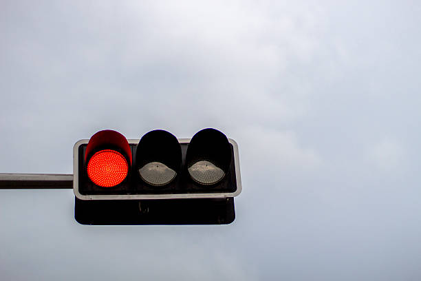 istock red traffic light in the overcast sky 484161170