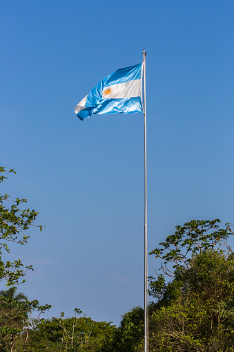 Blue and white Argentinian flag flying from a flagpole against a blue sky