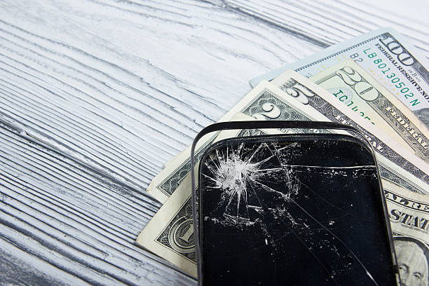istock Modern broken mobile phone and money on white wooden background. 484164150