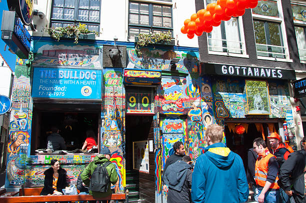 Amsterdam Bulldog coffeeshop in red-light district on King's Day. Amsterdam, the Netherlands - April 27, 2015: Famous Amsterdam Bulldog coffeeshop in red-light district in the midday on King's Day, crowd of people in orange on the street. wellen stock pictures, royalty-free photos & images