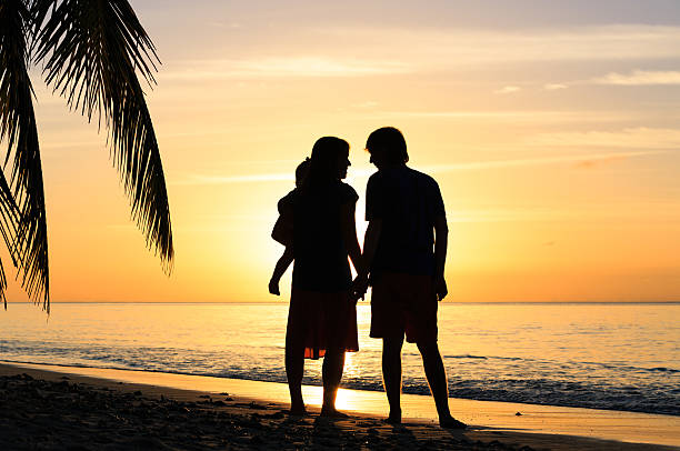 istock romantic couple with little child at sunset beach 484167934
