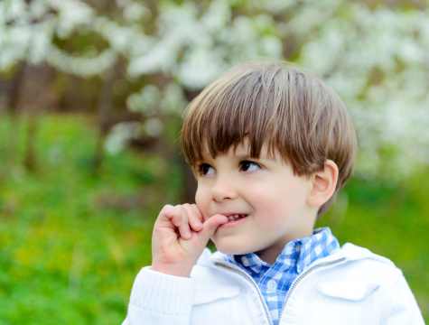 cute little boy biting finger and looking away, spring season.