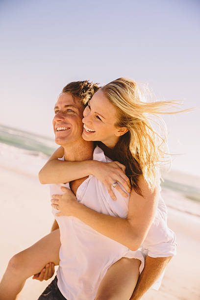 istock Man giving woman piggyback ride on beach 484169837