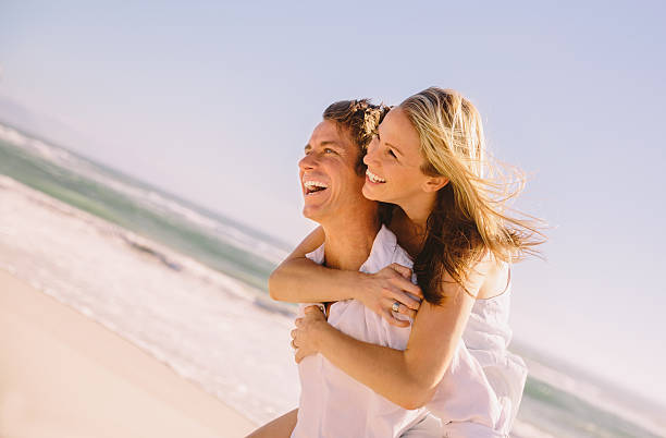 istock Man giving woman piggyback ride on beach 484169845