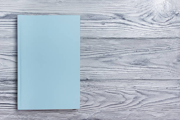 Blank book cover on textured wood background. Copy space